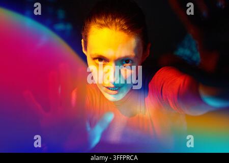 Futuristic portrait of a woman interacting with a colorful holographic interface in cyberspace, illustrating metaverse technology, virtual reality, ar Stock Photo