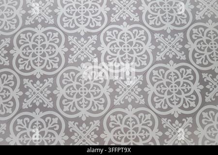 Close-up of gray ornamental ceramic tiles with repeating floral motifs, creating an elegant decorative background for a modern apartment interior or l Stock Photo