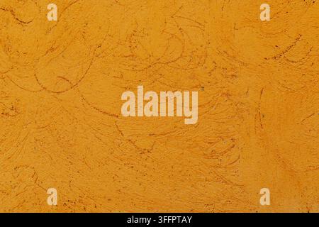Close-up of an orange stucco wall with rough weathered texture, subtle cracks, uneven plaster patterns, and warm earthy color, ideal for natural backg Stock Photo