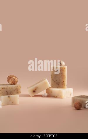 Handmade soap bars with botanical flecks are arranged in a minimalist still life with seashells on a warm neutral background, creating natural skincar Stock Photo