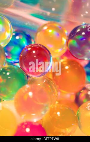 Vibrant close-up of translucent bubble spheres in rainbow colors, glowing with soft reflections and refractions to create a playful abstract backgroun Stock Photo