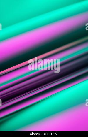 Abstract turquoise and magenta light streaks sweep diagonally across a dark background, creating a vibrant blurred texture with luminous bands and mod Stock Photo