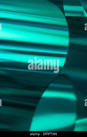 Abstract close-up of turquoise metallic material with reflective curved bands and dark shadows, creating a sleek futuristic background with luminous c Stock Photo