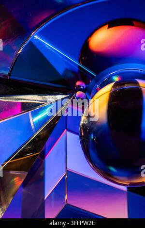 Vibrant abstract composition of reflective glass spheres and angular crystal surfaces illuminated by blue, magenta, and orange neon light, creating a Stock Photo