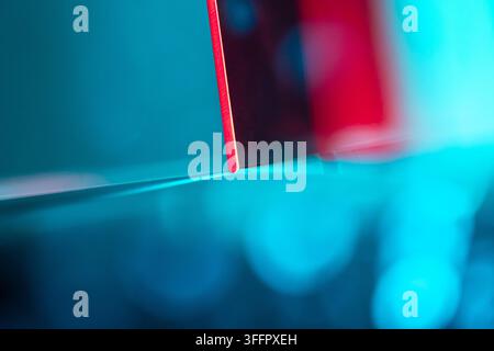 Close-up of a red geometric edge casting a fine shadow across a glowing cyan surface, creating an abstract futuristic composition with vivid contrast Stock Photo