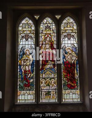 Three arched stained glass panels depicting Jesus Christ, angels and biblical figures in a Christian church window St Mary'sMarket Lavington Wiltshire Stock Photo