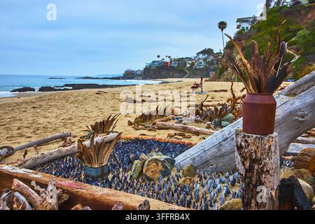 Feather Shrine on Driftwood at Thousand Steps Beach with Ocean and Cliffside Homes Stock Photo