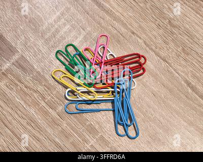 Colorful paper clips pile isolated on wooden table Stock Photo