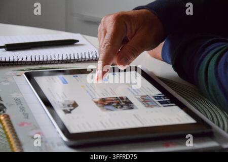 Stockholm, Sweden - 30 August 2026: Hands Planning and Booking a Trip on a Tablet with a Calendar and Notebook Nearby Stock Photo