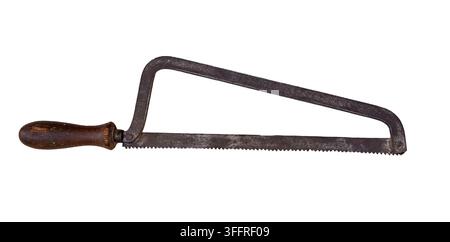 A vintage metal coping saw sits alone with a weathered wooden handle. The sharp teeth of the saw are clearly visible. It rests against a clean white b Stock Photo