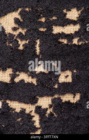A close up macro view of a black burnout textured fabric surface showing a contrasting woven beige background. Soft lighting highlights the tactile ma Stock Photo
