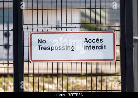 No Trespassing Access Interdit Sign on Black Chain-Link Fence Stock Photo