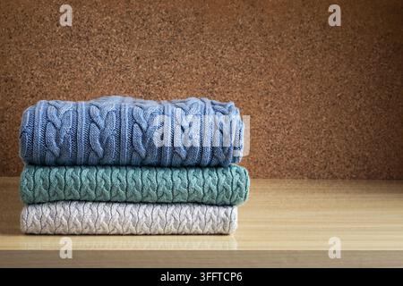 A stack of clothes, colored knitted woolen sweaters on the table Stock Photo