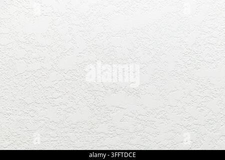 White textured wall surface with irregular raised plaster pattern, neutral backdrop, minimal background, abundant copy space. Stock Photo