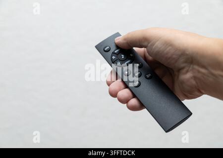 Hand holding RGB lighting remote control with color, speed, brightness, mode and timer buttons against clean neutral background. Stock Photo