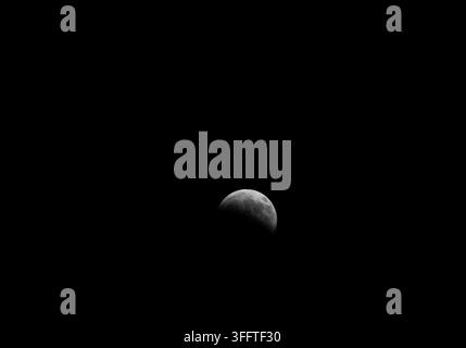 Lunar eclipse: the Earth casting its shadow on the Moon, viewed from the Amazon Rainforest in Brazil Stock Photo