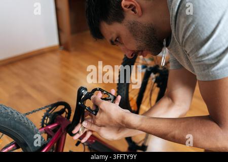 Close-up of mechanic fixing bike parts. Concentrated person doing DIY bicycle assembly, service indoors. Hobby, transport, active lifestyle concept. S Stock Photo