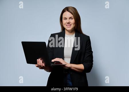 Female teacher holding laptop and looking at camera studio portrait Stock Photo