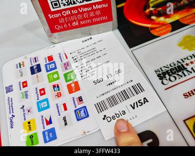 Singapore, Singapore - October 1, 2025: SGD 13 Visa receipt with barcode beside QR menu sign and Asian payment logos on restaurant table Stock Photo