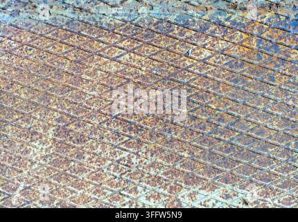 Rusty metal plate with diamond-shaped notches. Traces of corrosion and old cyan-colored paint are visible. Rough surface Stock Photo