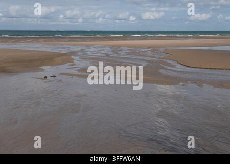 Shallow tidal channels spread across wet sand toward the sea forming natural patterns on the wide beach at Wissant on the Opal Coast in Pas de Calais Stock Photo
