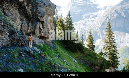 Discover the breathtaking beauty of Oeschinensee in Kandersteg, Switzerland. A hiker explores the stunning landscape with towering mountains, lush gre Stock Photo
