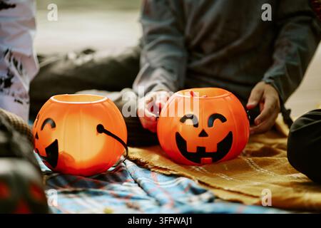 Children Sitting with Orange Halloween Pumpkin Buckets Outdoors Stock Photo