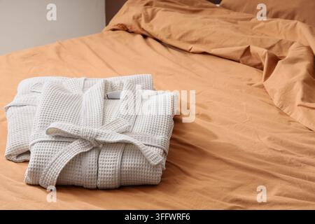 Folded waffle bathrobes on bed in room Stock Photo
