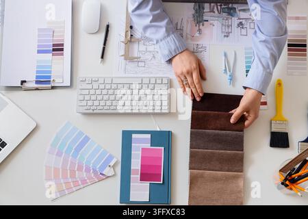 Female interior designers hands with fabric samples working on table, top view Stock Photo