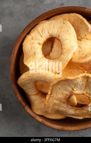 Dried apple rings in wooden bowl on grey backdrop Stock Photo