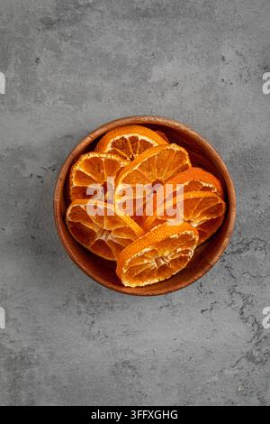 Dried orange slices in wooden bowl on stone Stock Photo