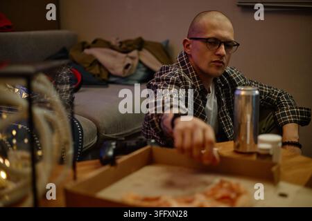 Man Reaching for Pizza While Playing Video Games at Home Stock Photo