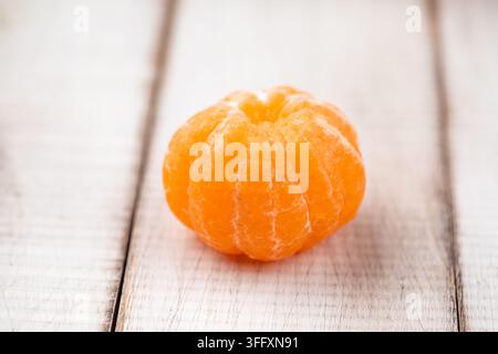 Peeled mandarin orange on wooden table Stock Photo