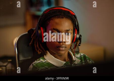 Focused Black Man Wearing Headset Playing Video Games at Night Stock Photo
