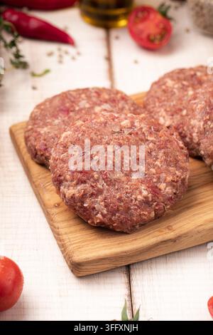 Raw minced meat patties on board with herbs Stock Photo