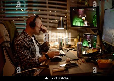 Tired Man Feeling Eye Strain While Playing Video Games at Night Stock Photo