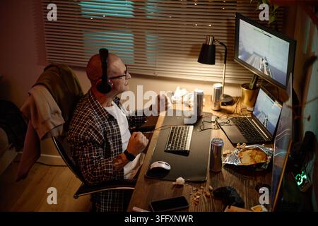 Excited Man Playing Online Video Games on Computer at Night Stock Photo