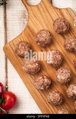 Raw minced beef meatballs on wooden board Stock Photo