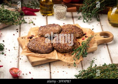 Fried beef cutlets on wooden board with herbs Stock Photo