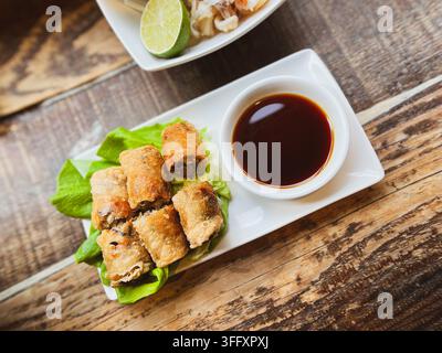 Crispy fried spring rolls served on lettuce leaves with a soy dipping sauce, at a Vietnamese restaurant, England, UK Stock Photo