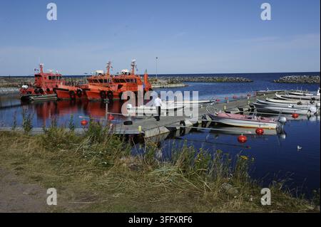 Bright orange Finnpilot maritime vessels docked along a tranquil wooden pier in a scenic Finnish coastal harbor during summertime. Stock Photo
