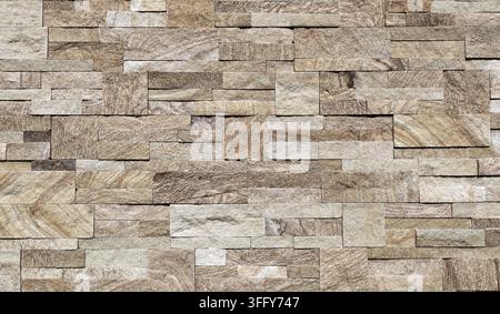 Elegant beige wall covering made of bricks and cubes of porcelain stoneware with stone effect. Background and texture. Stock Photo