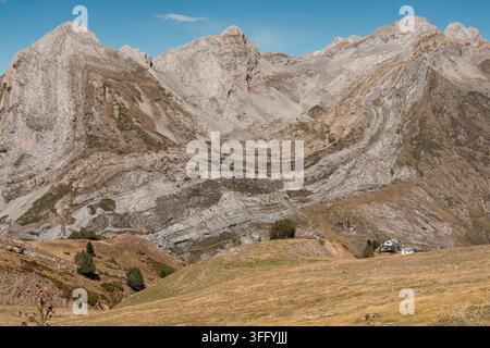 Monumental folded limestone rising above golden alpine pastures in clear Pyrenean light (Artouste, France: 26-aug-2026) Stock Photo