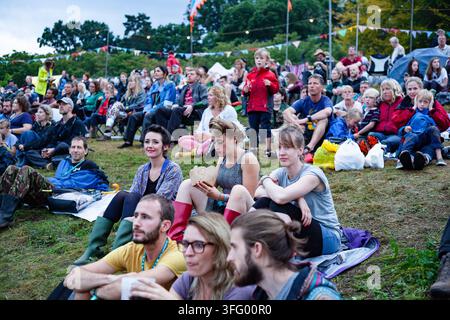 CROWD WATCHING FROM A GRASSY BANK, REPORTAGE, GREEN MAN FESTIVAL 2015, BRECON, WALES, UK, 2015: A large, diverse crowd of people of all ages sits together on a grassy bank to watch a performance at an outdoor summer festival. Photo: Rob Watkins. INFO: The Green Man Festival is held annually in the Brecon Beacons in August. It celebrates alternative music, arts, literature, science and family-friendly culture in a beautiful mountain setting. The 2015 event started sunny but turned muddy with overnight rain on the final two days. Stock Photo