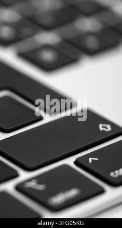 Vertical extreme close up view of a modern black laptop keyboard keys with white letters Stock Photo