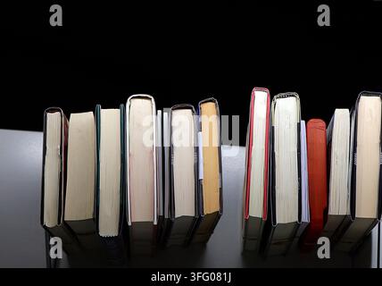 Symmetrical rows of colorful books arranged in two clusters on a dark background. Stock Photo