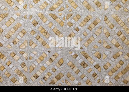 Geometric Terrazzo Surface with Beige Stone Inlays. Close view of gray terrazzo with beige stone fragments arranged in a geometric diagonal pattern. Stock Photo