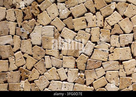 Irregular Beige Travertine Stone Mosaic Texture. Close view of beige travertine stone pieces arranged in an irregular porous mosaic pattern. Stock Photo