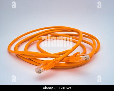 Orange Ethernet Cable Connector Close-up - A detailed close-up shot of an orange Ethernet cable with an RJ45 connector, highlighting network connectiv Stock Photo