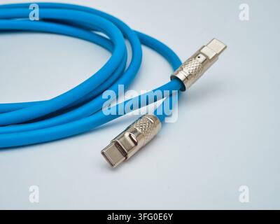 Blue USB C Cable Coiled with Leather Str - A bright blue USB-C data and charging cable is neatly coiled and secured with a small orange leather strap Stock Photo